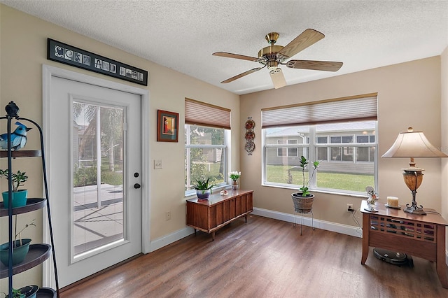 doorway to outside with a textured ceiling, dark wood-type flooring, and ceiling fan