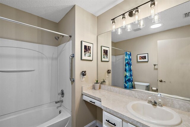 full bathroom featuring a textured ceiling, shower / tub combo with curtain, vanity, and toilet