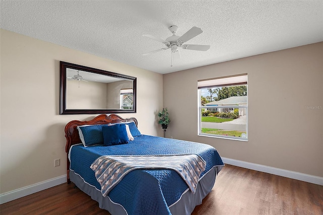 bedroom with ceiling fan, wood-type flooring, and a textured ceiling