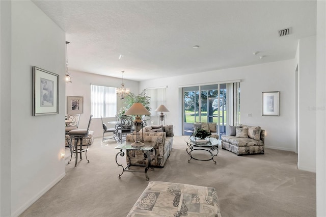 carpeted living room with a textured ceiling, an inviting chandelier, and a wealth of natural light