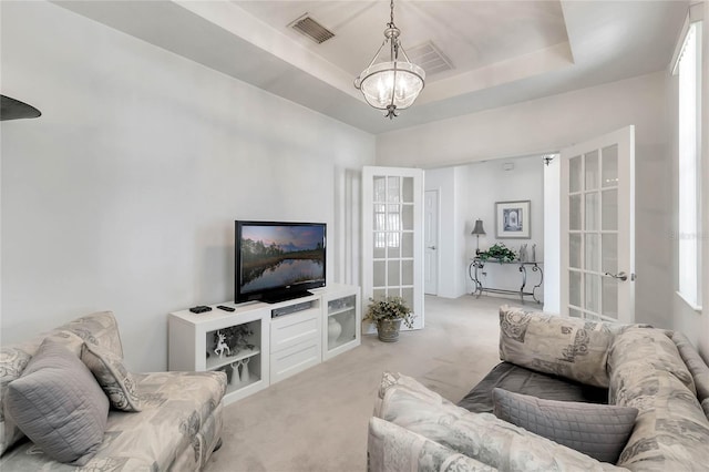 living room with light carpet, french doors, an inviting chandelier, and a raised ceiling