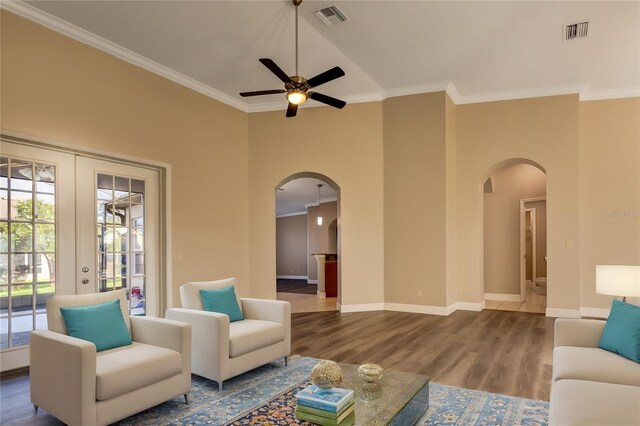 living room with ceiling fan, french doors, a towering ceiling, hardwood / wood-style flooring, and ornamental molding