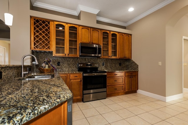 kitchen with hanging light fixtures, sink, crown molding, dark stone countertops, and appliances with stainless steel finishes