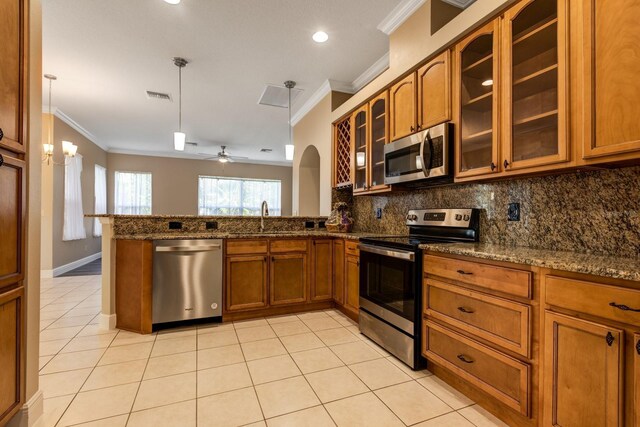 kitchen with sink, stainless steel appliances, stone countertops, ceiling fan with notable chandelier, and ornamental molding