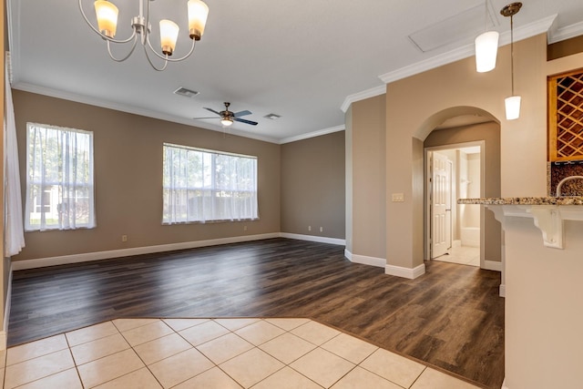 empty room featuring ornamental molding, light hardwood / wood-style flooring, ceiling fan, and a healthy amount of sunlight