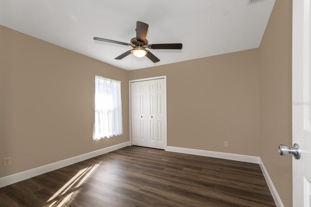 empty room with ceiling fan and dark hardwood / wood-style flooring