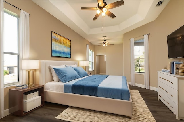 bedroom with ceiling fan, a raised ceiling, and dark wood-type flooring