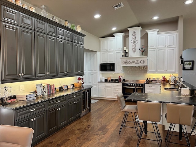 kitchen featuring dark hardwood / wood-style floors, a kitchen bar, electric range oven, sink, and black microwave