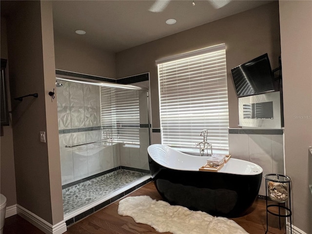 bathroom featuring hardwood / wood-style floors, toilet, plus walk in shower, and ceiling fan