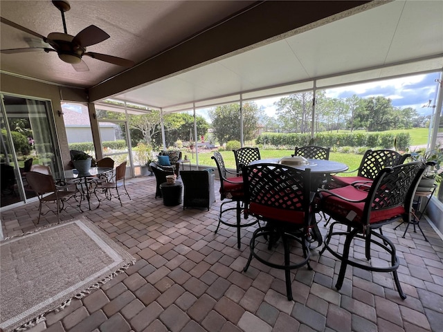 sunroom / solarium featuring beamed ceiling and ceiling fan