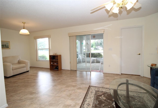 tiled living room with ceiling fan and a textured ceiling