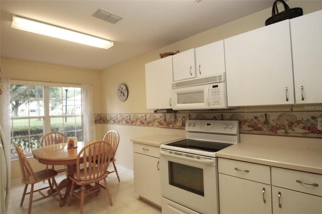 kitchen with light tile patterned flooring, white appliances, and white cabinets