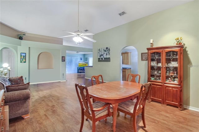 dining area with arched walkways, visible vents, a ceiling fan, and light wood-style floors