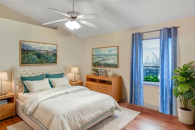 bedroom with ceiling fan, light wood-style floors, and vaulted ceiling