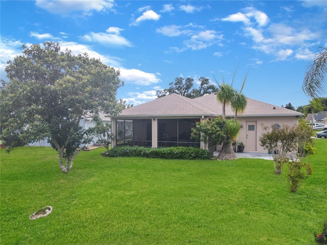 rear view of property featuring a lawn, a sunroom, and stucco siding