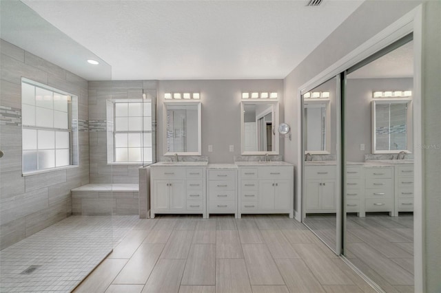 bathroom featuring vanity, a bath, and a textured ceiling