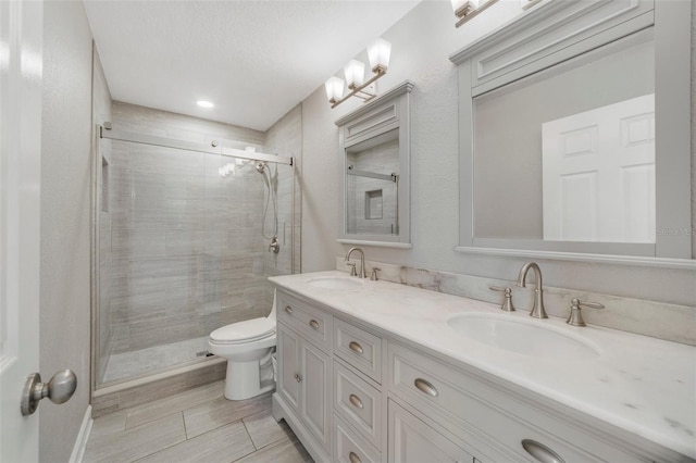 bathroom featuring walk in shower, vanity, a textured ceiling, and toilet