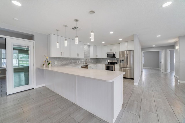 kitchen with white cabinetry, hanging light fixtures, stainless steel appliances, tasteful backsplash, and kitchen peninsula