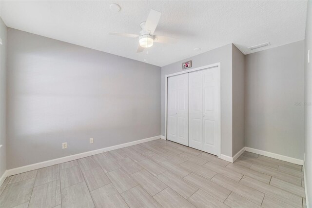 unfurnished bedroom with a textured ceiling, a closet, and ceiling fan