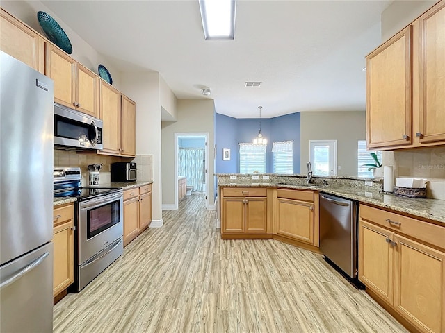 kitchen with a notable chandelier, stainless steel appliances, kitchen peninsula, decorative backsplash, and light hardwood / wood-style floors