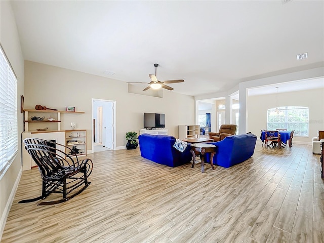 living room featuring ceiling fan with notable chandelier and light wood-type flooring