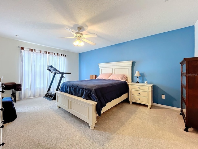 bedroom with ceiling fan, light carpet, and a textured ceiling