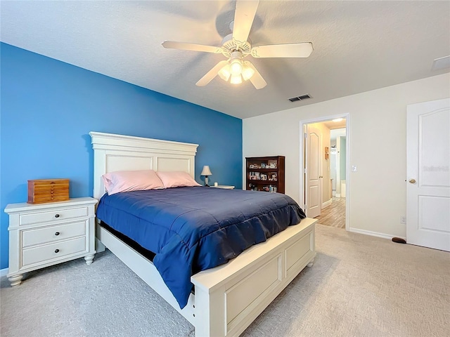 carpeted bedroom with ceiling fan and a textured ceiling