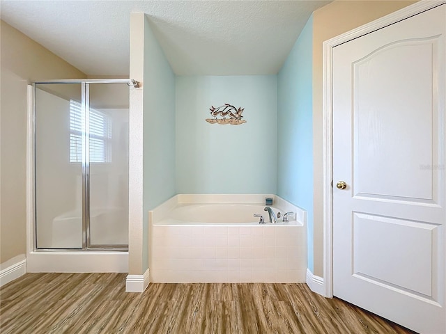 bathroom with a textured ceiling, wood-type flooring, and plus walk in shower