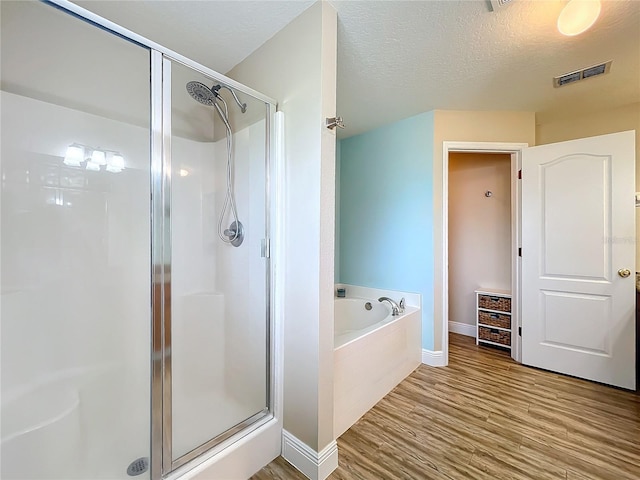 bathroom featuring a textured ceiling, shower with separate bathtub, and wood-type flooring