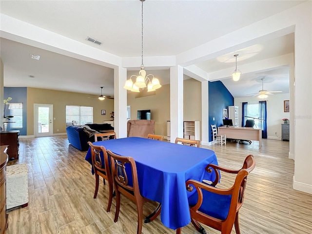 dining room featuring light wood-type flooring, ceiling fan with notable chandelier, and vaulted ceiling