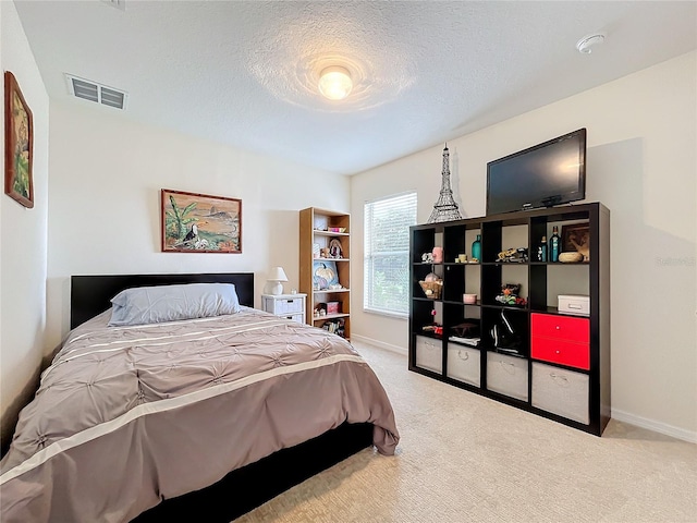 bedroom with a textured ceiling and light colored carpet