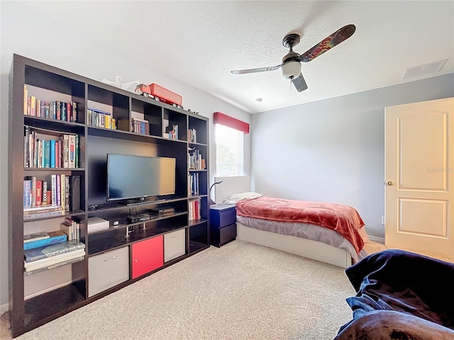 bedroom with ceiling fan, carpet, and a textured ceiling