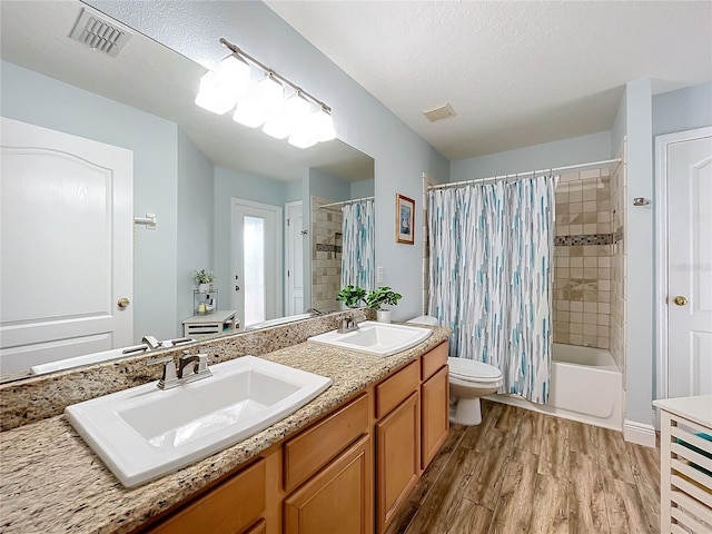 full bathroom with toilet, vanity, a textured ceiling, shower / bath combo, and hardwood / wood-style flooring