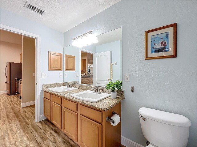 bathroom featuring a textured ceiling, vanity, toilet, and hardwood / wood-style flooring