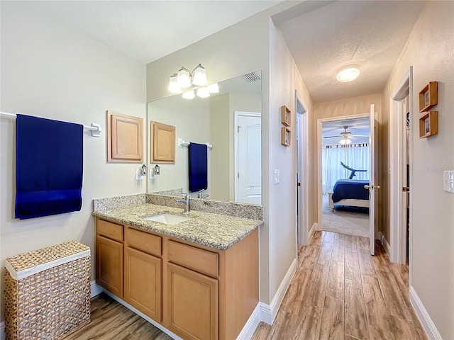 bathroom featuring a textured ceiling, vanity, ceiling fan, and wood-type flooring