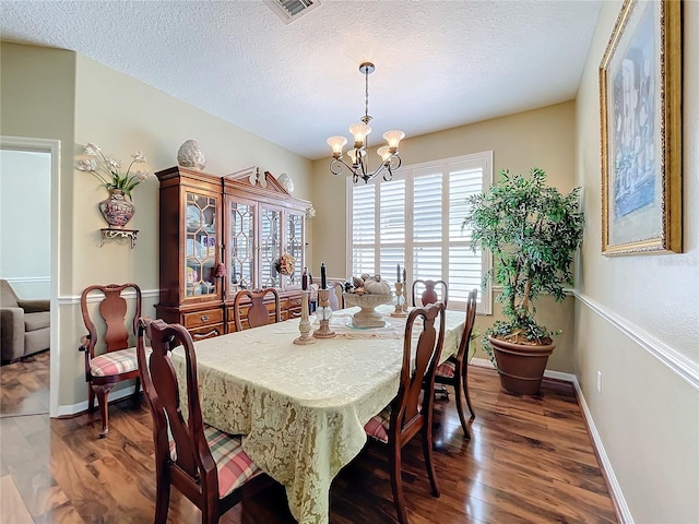 dining room featuring dark hardwood / wood-style flooring, an inviting chandelier, and a textured ceiling