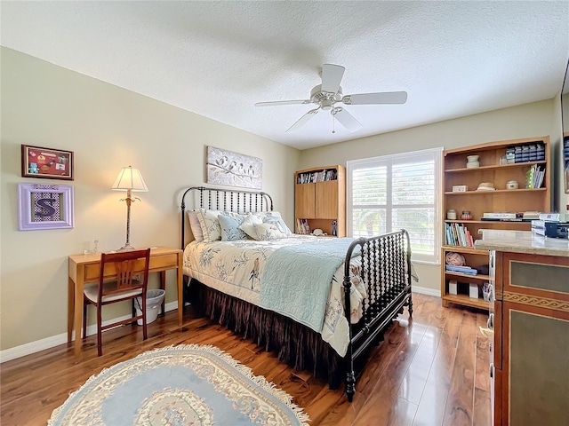 bedroom with a textured ceiling, ceiling fan, and dark hardwood / wood-style floors