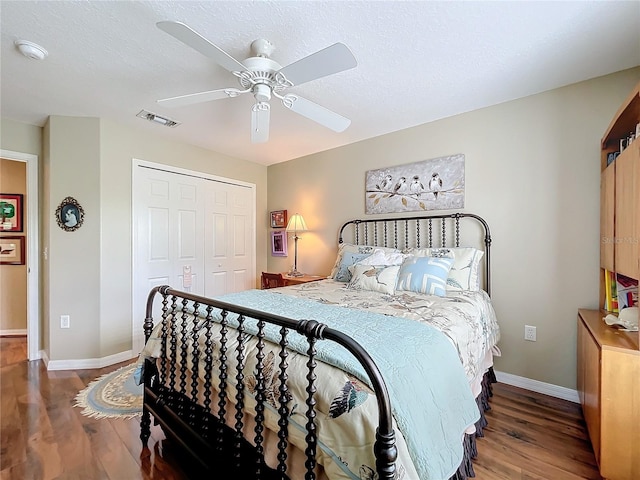 bedroom with dark wood-type flooring, a closet, ceiling fan, and a textured ceiling