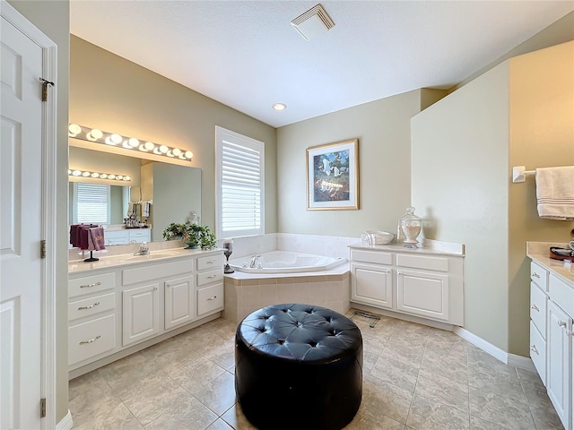 bathroom featuring vanity, a relaxing tiled tub, and tile patterned floors