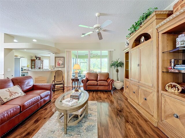 living room featuring a textured ceiling, ceiling fan, and dark hardwood / wood-style floors