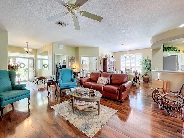 living room featuring a textured ceiling, dark wood-type flooring, and ceiling fan with notable chandelier