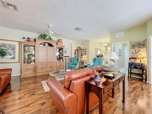 living room with ceiling fan with notable chandelier, a textured ceiling, and wood-type flooring