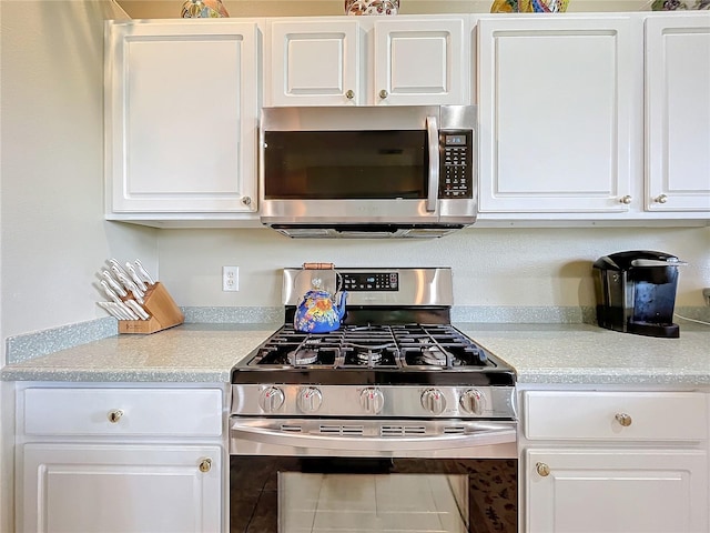 kitchen featuring white cabinetry, stainless steel appliances, and tile patterned flooring