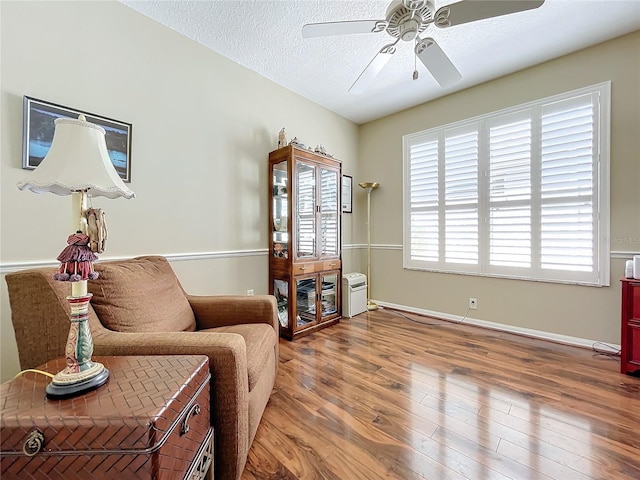 sitting room with ceiling fan, hardwood / wood-style flooring, and a textured ceiling