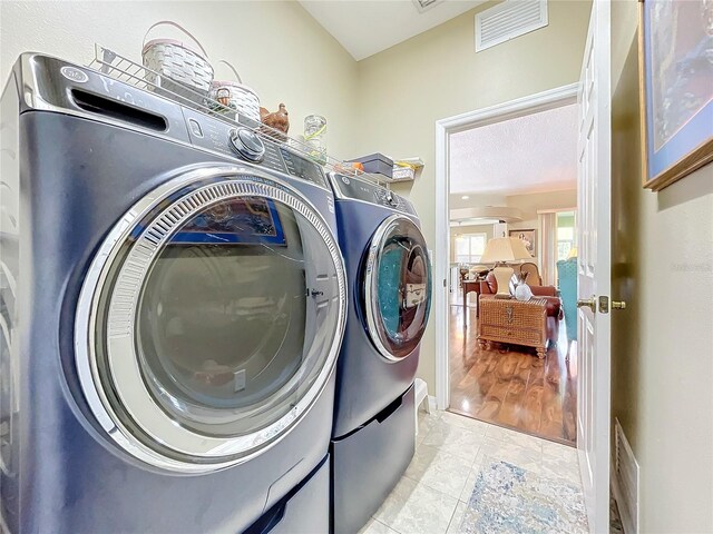 laundry area with washer and dryer and light hardwood / wood-style flooring