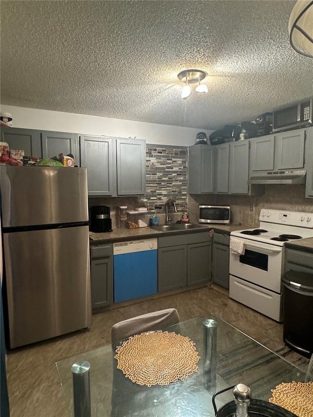 kitchen featuring appliances with stainless steel finishes, sink, a textured ceiling, and decorative backsplash