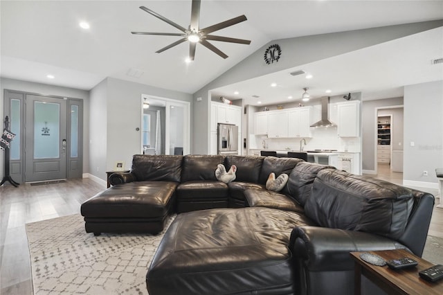 living room with light hardwood / wood-style flooring, vaulted ceiling, and ceiling fan