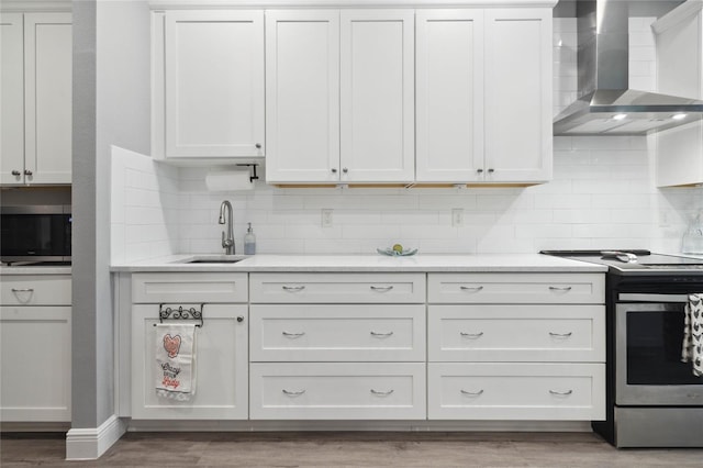 kitchen featuring hardwood / wood-style floors, sink, decorative backsplash, appliances with stainless steel finishes, and wall chimney range hood