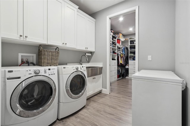 washroom with cabinets, washer and clothes dryer, sink, and light hardwood / wood-style floors