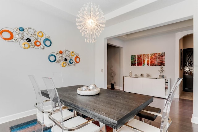 dining space with hardwood / wood-style floors and a notable chandelier